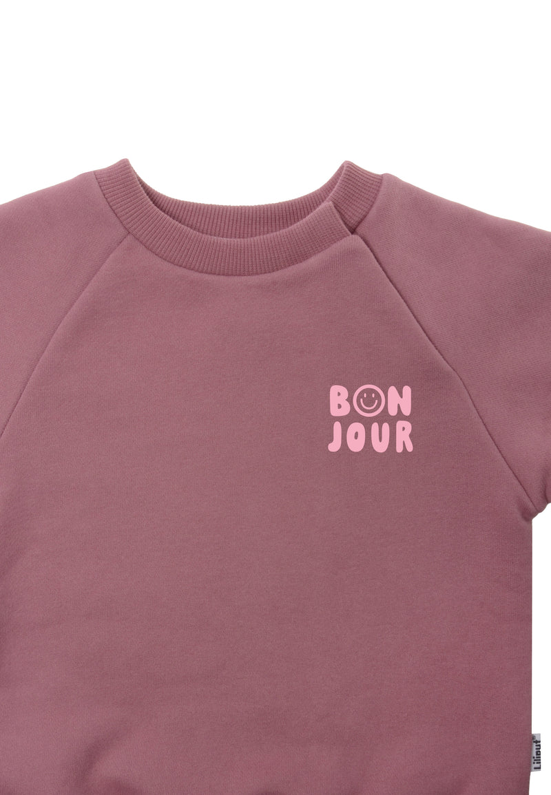 Detailansicht des rosè farbenden Sweaters mit hellrosanem Aufdruck Bonjour.