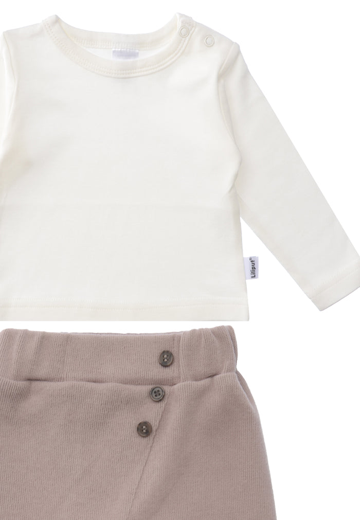 Detailfoto Zweiteiliges Set bestehend aus Langarmshirt in ecru mit zwei Druckknöpfen auf der Schulter für leichtes An.- und Ausziehen und Ribstrick Hose in braun mit schräger Naht und drei aufgesetzten Knöpfen. Mit umgeschlagenem Saum an den Füßen.