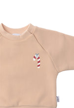 Detailansicht des beigen Kinder Sweaters in weicher Qualität mit niedlich-weihnachtlicher Zuckerstange als Aufdruck.