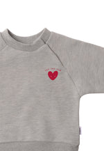 Detailansicht des grauen Sweatshirt mit rotem Herz als Aufdruck.