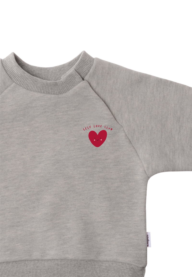 Detailansicht des grauen Sweatshirt mit rotem Herz als Aufdruck.