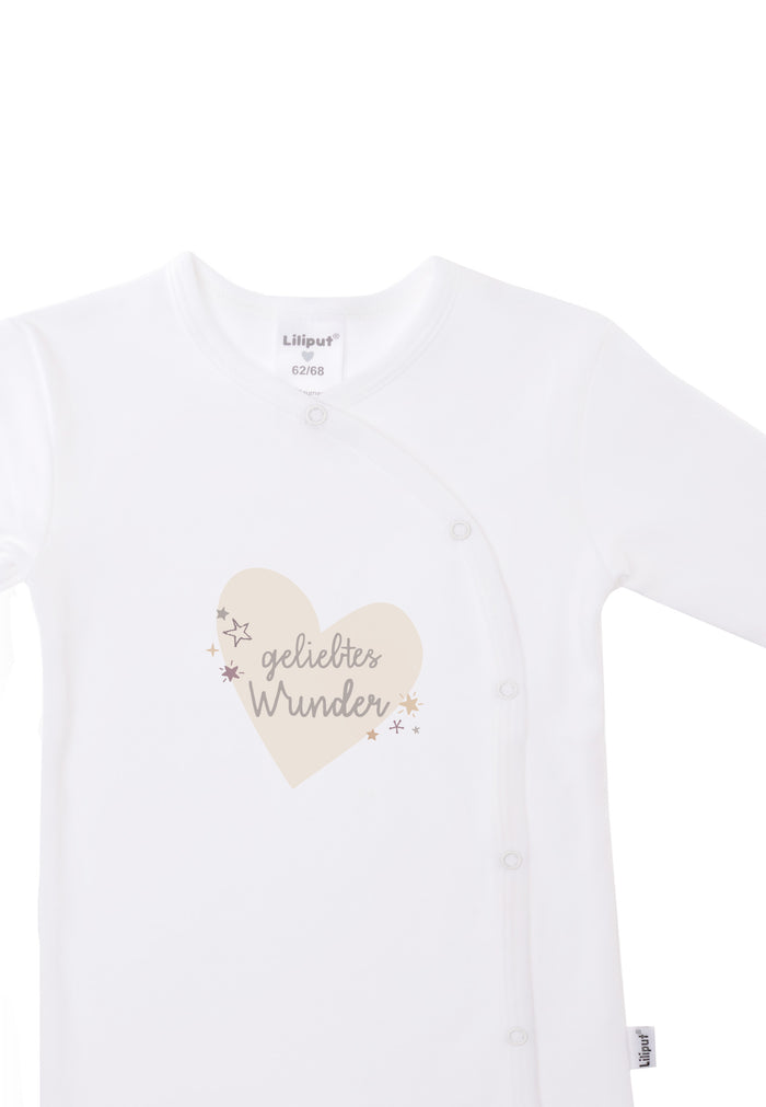 Detailaufnahme des weißen Overalls mit schräger Druckknopfleiste und dezentem Print auf der Vorderseite.