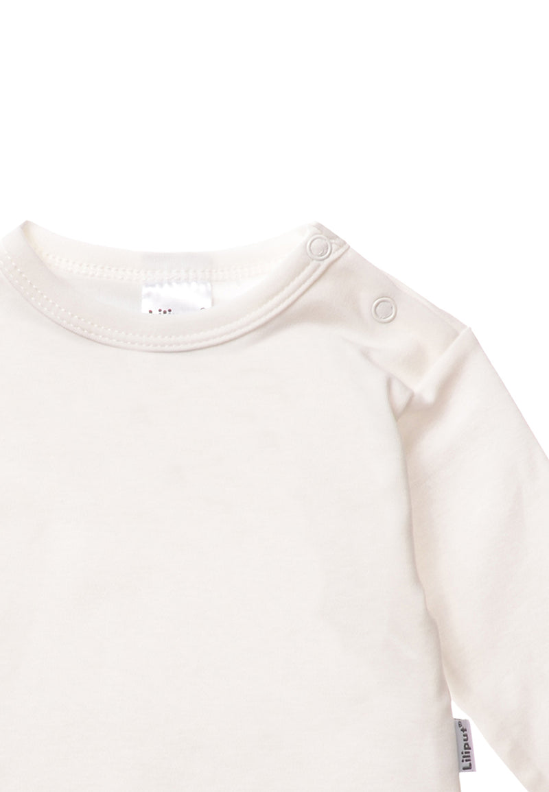 Detailaufnahme Langarmshirt in ecru mit praktischem Druckknopf auf der Schulter für ein leichtes An- und Ausziehen.